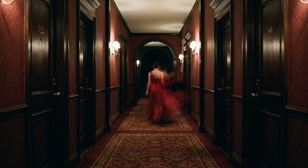 A ghostly lady in red walks a hallway.